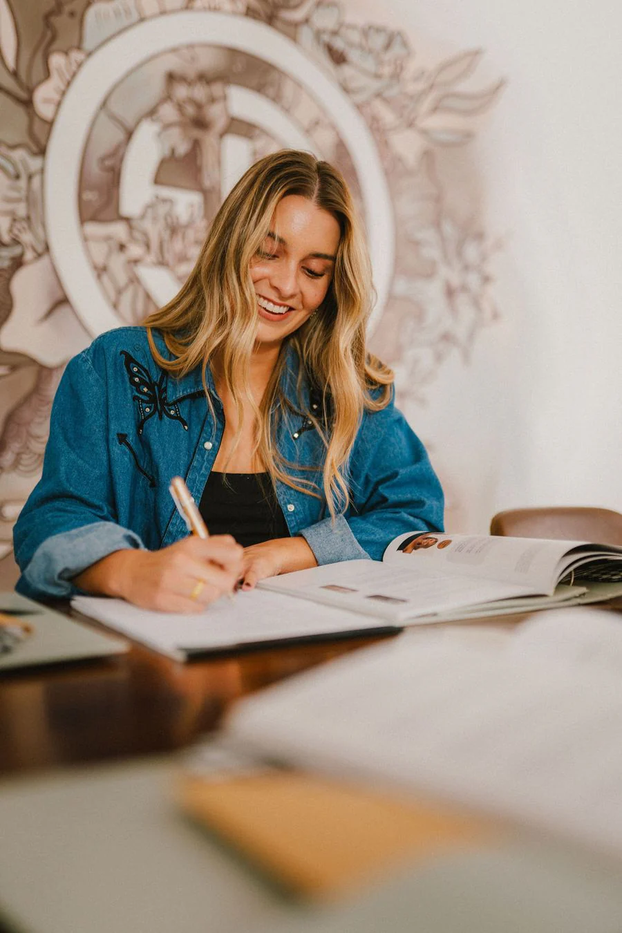 A student taking notes beside an open spray tan course workbook