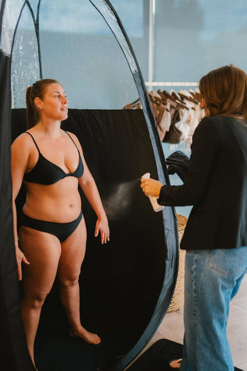 A Sjolie educator demonstrating skin preparation on a model during spray tan training